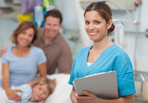Nurse holding a clipboard next to a family in hospital ward